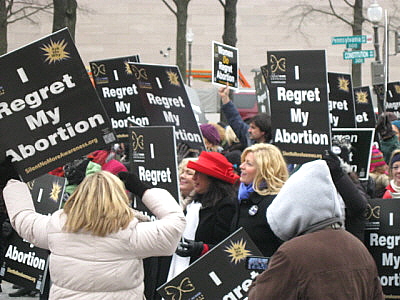 Women carry signs that say, 'I Regret My Abortion'