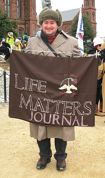 Man holds banner for <em>Life Matters Journal</em>