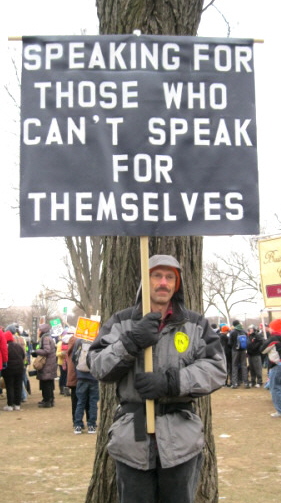 Man with sign: 'Speaking for Those Who Can't Speak for Themselves'