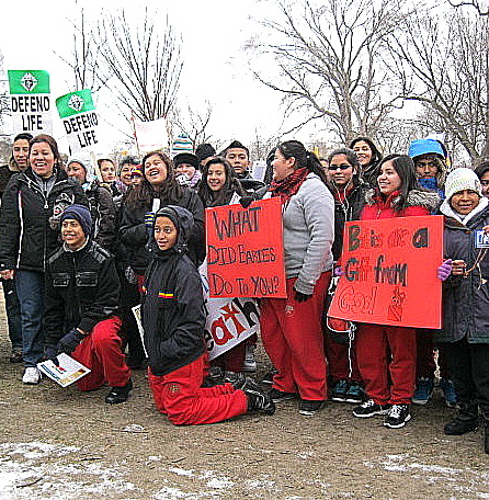 Hispanic marchers with signs including 'What Did Babies Do To You?'