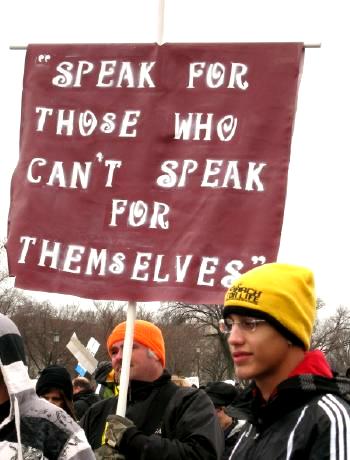 Man and boy with banner that says, 
'Speak for Those Who Can't Speak for Themselves'