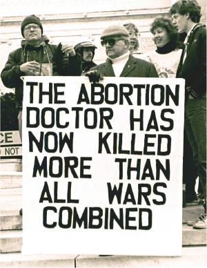 Man with sign: 'The Abortion Doctor Has Now Killed More than All 
Wars Combined'