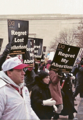 Demonstrators with signs: 'I Regret My Abortion' and 'I Regret Lost Fatherhood'